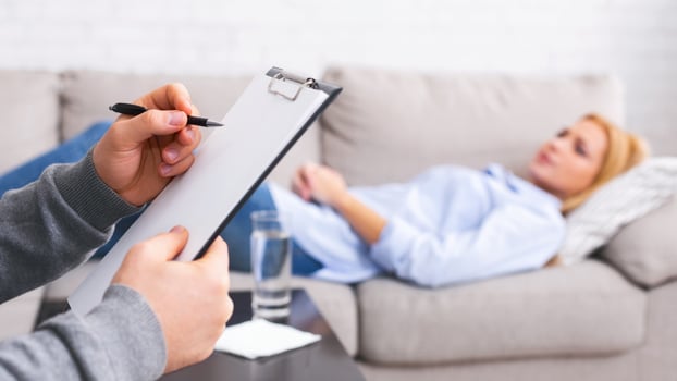 Mental health and counseling concept. Psychologist listening to depressed female patient and writing down notes, panorama photo
