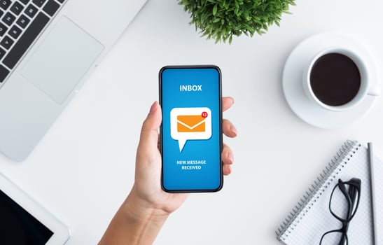 Email marketing and newsletter concept. Top view of unrecognizable young woman holding modern mobile phone with new mail notification on screen, creative collage photo