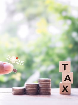 Close up hand putting coin into stack of coins and Wooden blocks with the word TAX. The concept about saving money and manage time to paying tax photo