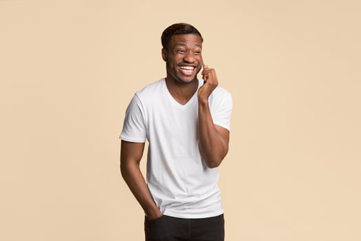 Afro Man Talking On Phone And Laughing Standing Over Yellow Background In Studio. Free Space For Text photo