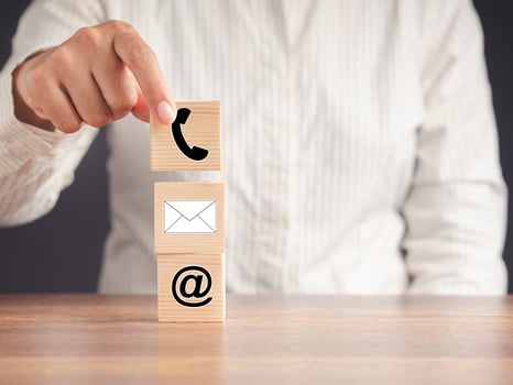 Contacts us. Hand holding a wooden cube with icon symbol telephone, email, address photo