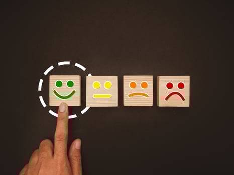 Overhead view of hand push green smiley face emoticon on the wooden cube over a black background photo