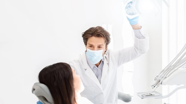 Attentive handsome dentist in mask listening to female patient, copy space photo