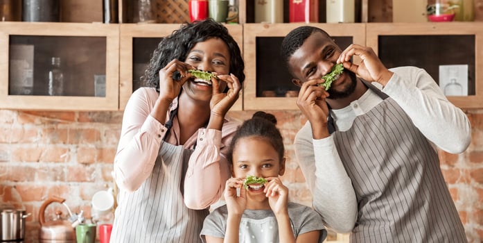 Kitchen Fun. Sweet african american family having fun while cooking, making salad mustache, copy space photo