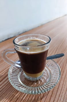 Coffee and milk have not been stirred in a glass on the table photo