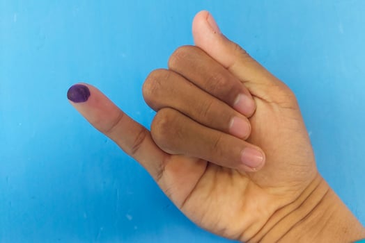 Ink marks marked by the election on the little finger with a blue background photo