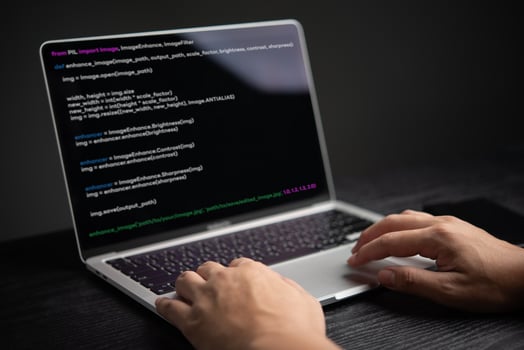 A person typing on a laptop with code on it photo