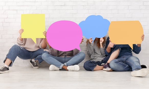 Friends carrying empty speech bubble icons, closing their faces over brick wall photo