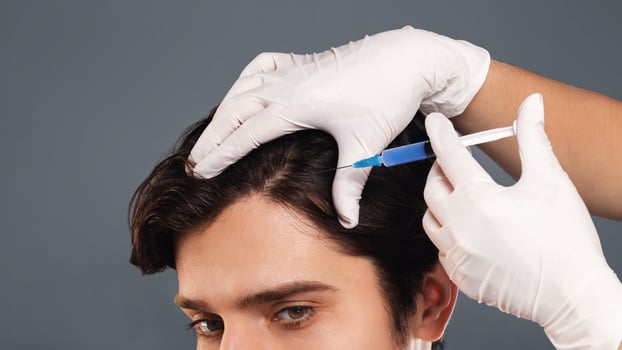 Mesotherapy of hair. Young man getting injections in head, grey panorama background, empty space photo