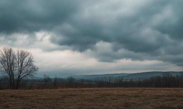 Overcast sky looming above a quiet countryside, thick gray clouds covering the entire sky photo