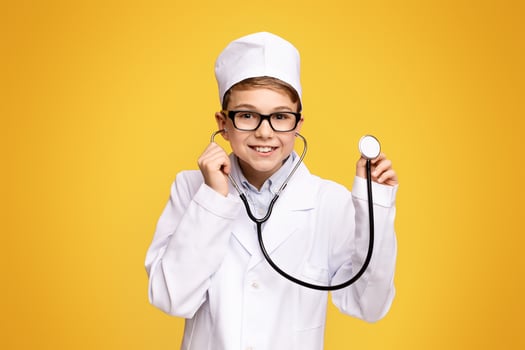 Cheerful teen boy in doctor uniform holding stethoscope, ready for checkup, empty space photo
