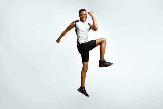 Number One. Full length portrait of excited black sportsman celebrating triumph jumping over red studio background photo