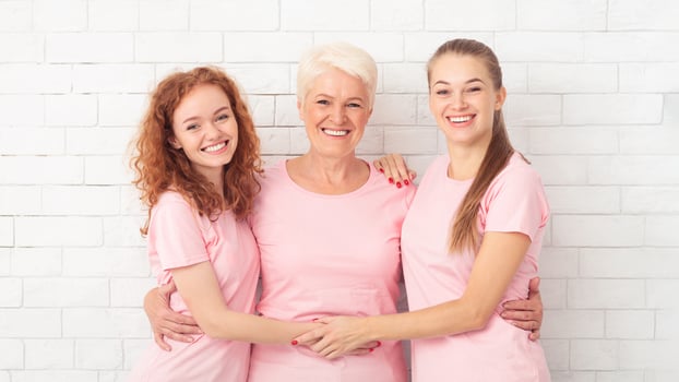 Three Breast Cancer Volunteers Ladies Posing Wearing Pink Ribbon T-Shirts Hugging Over White Background photo