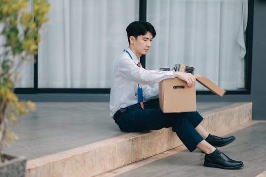 Sadness depressed Businessman with box cardboard packing personal items after losing jobs. Failure businessman sitting at stair front of building. Your fired Unemployed Jobless People Crisis photo