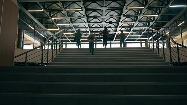 Back view fast unrecognizable schoolboys schoolgirls together running children run on stairs little classmates pupils Caucasian African kids boys girls rush hurry school corridor dark hall upstairs photo