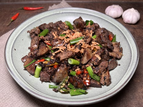 Tumis Ati Goreng is a popular Indonesian stir-fried chicken liver dish known for its rich, savory flavors and spicy kick served on a plate with fried onion sprinkles. photo