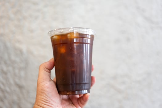 Hand holding a glass of iced black coffee photo