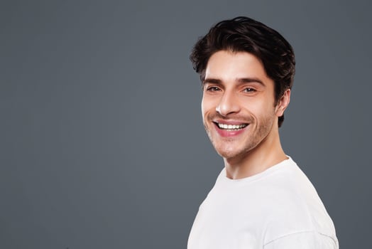 Semi profile portrait of cheerful caucasian guy on grey background photo