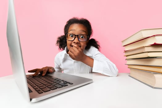 Online Education. Shocked School Girl Sitting At Laptop Biting Nails Learning From Home. Yellow Background photo