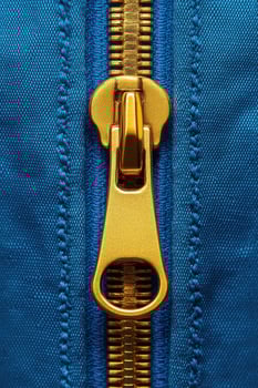 Golden zipper fastener on blue fabric showing macro detail of teeth photo