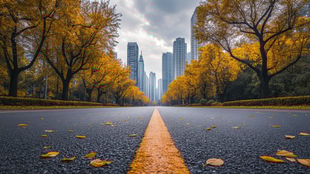 A quiet road framed by towering trees with vibrant autumn leaves leads to a stunning cityscape, showcasing the splendor of fall within a peaceful urban setting, enticing exploration photo