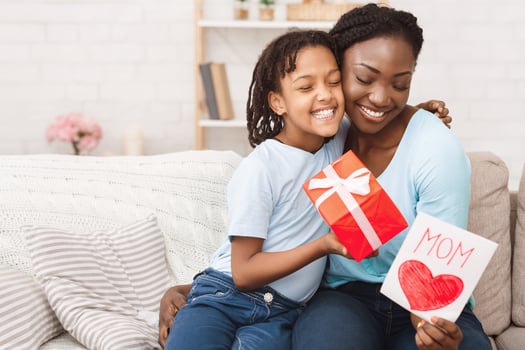 Congatulations. Black kid embracing mom, giving gift box and greeting card to her, copyspace photo