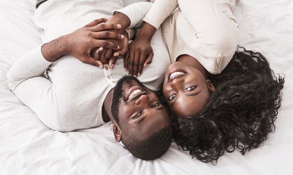 Portrait of young african american couple in love lying on bed together, top view photo