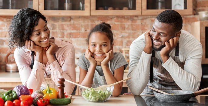 Happy afro family cooking healthy dinner together at kitchen, posing at camera, making salad, panorama with copy space photo