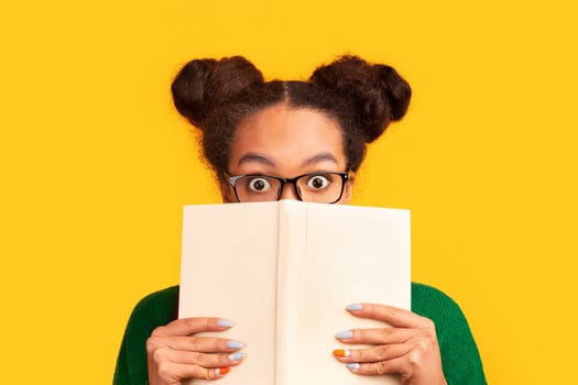 College Exams. Shocked black girl covering face with book, hiding behind it with eyes wide open. Panorama, copyspace photo