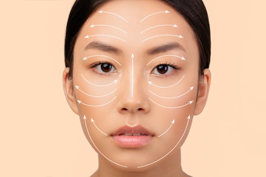 Cosmetology And Facial Skin Enhancement. Portrait Of Japanese Lady Featuring Face With Lifting Arrows On White Background. Headshot Of Woman Advertising Plastic Surgery And Face Sculpting Massage photo