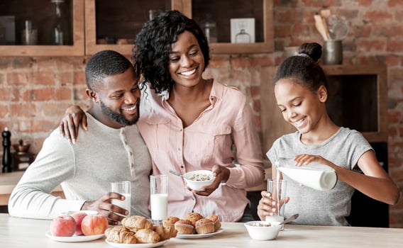 Vitamins and minerals. Beautiful black family having breakfast together, girl pouring milk, copy space photo