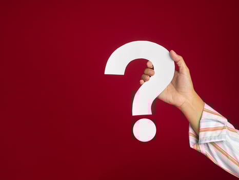 Hand holding a white question mark against a red background photo
