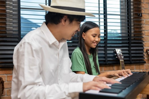 Young asian girl is learning how to play keyboard from her teacher in the after school music class for education children skill and talent development concept photo