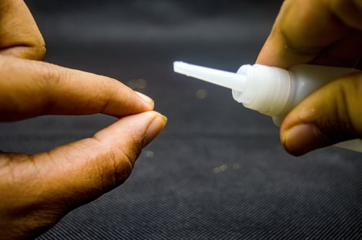 Close up of hands applying cyanoacrylate ethyl adhesive, showcasing precision and strength. Ideal for DIY projects, repairs, and crafts. The focus is on the nozzle and a drop of glue photo
