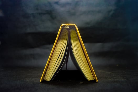 Open Quran book with golden edges on dark background, showcasing intricate Arabic script, symbolizing Islamic faith and spirituality photo