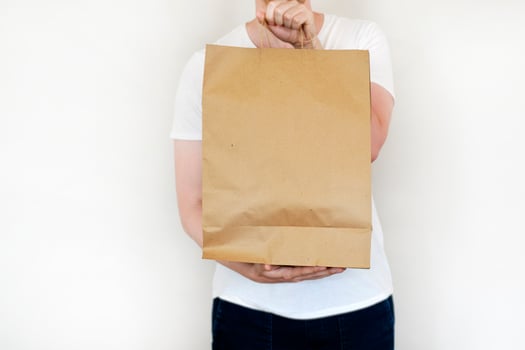 Caucasian delivery man carrying package paper bag. Isolated on white studio Background. Shopping sale concept. Mockup template. Copy space. photo