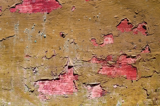 Close up of a wall with peeling red paint, revealing rough brown textures underneath. This image highlights the contrast between vibrant red and earthy brown, depicting decay and vintage appeal. photo
