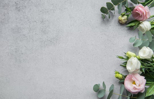 Delicate arrangement of mixed flowers and eucalyptus leaves on a light grey surface photo