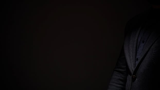 A man in a suit is standing in the dark photo
