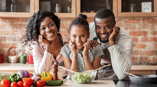 Adorable afro family cooking healthy dinner together at kitchen, posing at camera, making salad, copy space photo