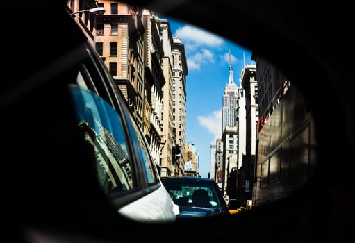 A car mirror showing a city street with buildings in the background photo