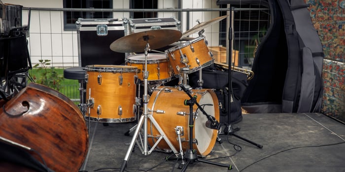 Drum set on outdoor stage with closed double bass case, musical instruments setup, performance concept photo