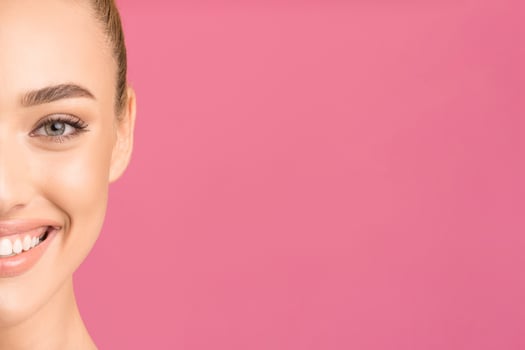 This image features a close up of a woman face. Only half of her face is visible, and her mouth is slightly open in a wide smile. Her eyes are closed and her teeth are perfectly white, copy space photo
