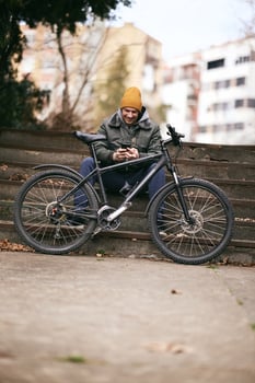 Man Using Smartphone While Sitting Next to his Mountain Bike photo