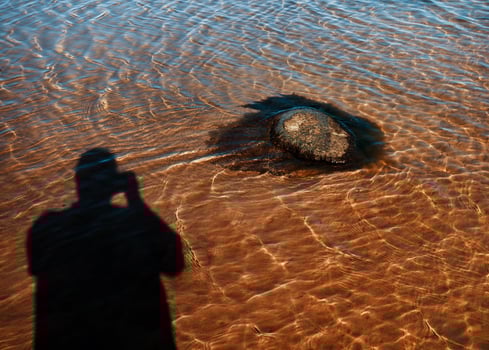 A shadow of a person standing in shallow water photo