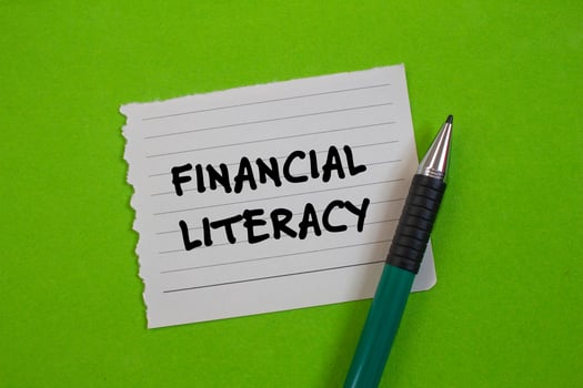 Financial literacy message written on ripped torn paper with a pen on green background. Conceptual financial literacy symbol. Copy space. photo