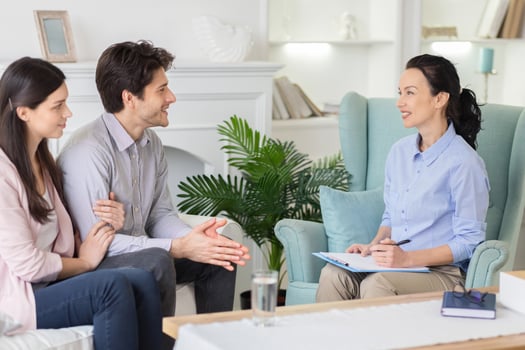 In a soothing therapy room, a young couple consults with a lady psychologist, seeking advice to strengthen their relationship in a supportive and empathetic environment. photo