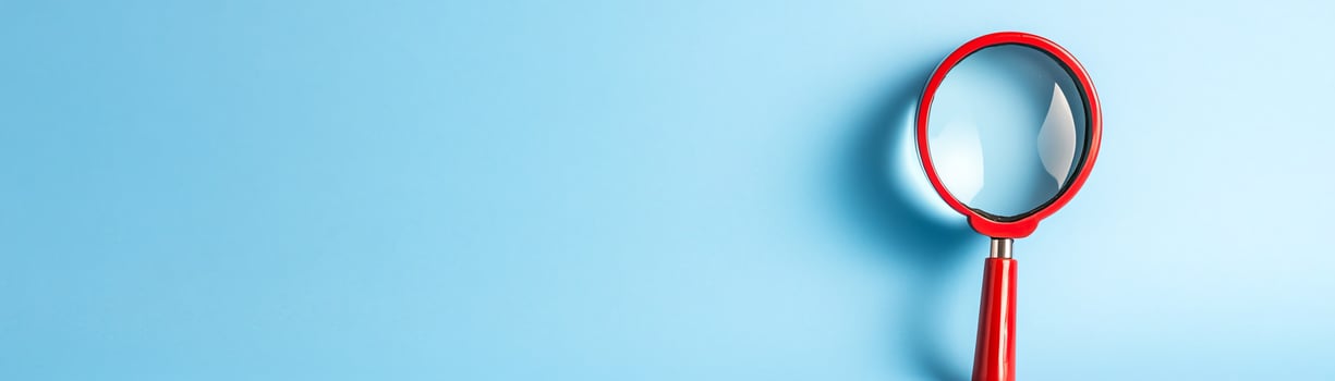 Close-up of a red magnifying glass on a light blue background. The image represents exploration, search, and discovery with simplicity and clarity. photo