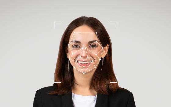 A woman in professional attire smiles as facial recognition patterns are superimposed on her face. photo
