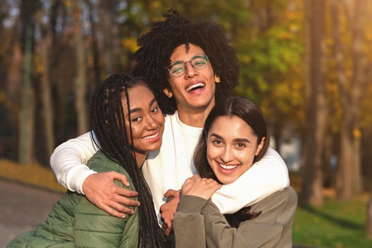 Cheerful african guy hugging his smiling girlfriends over park background photo